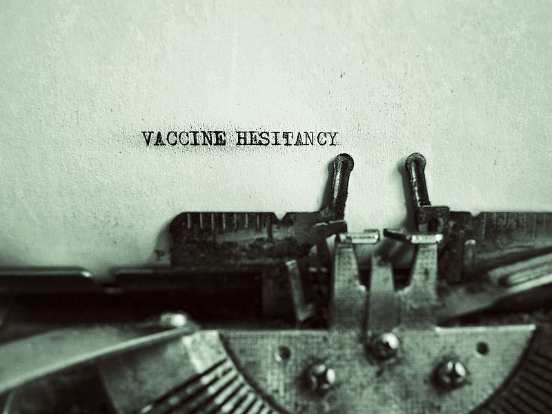 pic of typewriter with words vaccine hesitancy on white paper